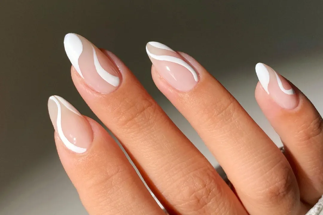Almond nails in sheer nude with white swirl French tips